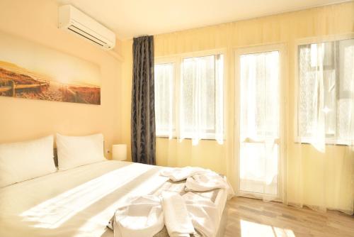 1 dormitorio con cama blanca y ventanas en Central studio #3, en Burgas