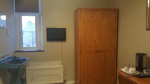 a bathroom with a sink and a wooden door at Maindee Guest House in Barrow in Furness