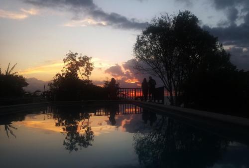 two people standing next to a swimming pool at sunset at Punta Duarte Garden Inn in Los Duarte