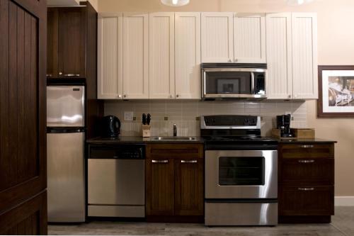 a kitchen with a stove top oven, microwave and refrigerator at Summerland Waterfront Resort & Spa in Summerland