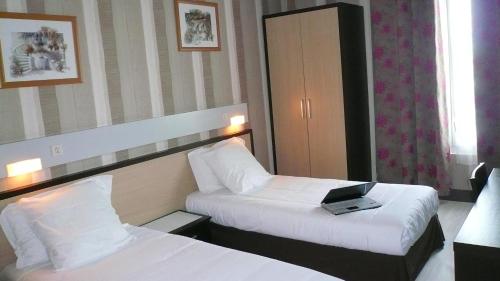 a hotel room with two beds and a laptop on the bed at Hôtel L'Européen in Tarbes