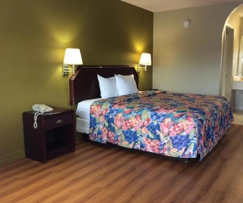 a hotel room with a bed and a phone on a table at Stratford House Inn and Suites Temple in Temple
