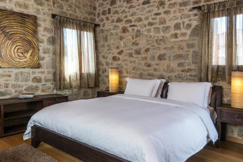 a bedroom with a large bed and a stone wall at Elafos Spa Hotel in Elliniko