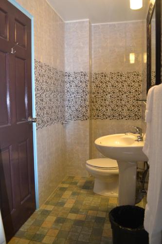 a bathroom with a toilet and a sink at Montecristo Inn in Piarco