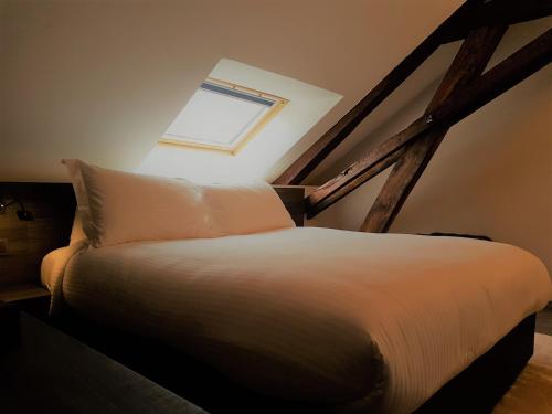 a bedroom with a white bed with a window at Etoile de Pompadour in Arnac-Pompadour