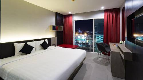 ein Hotelzimmer mit einem Bett, einem Schreibtisch und einem Fenster in der Unterkunft Neon Patong in Patong Beach