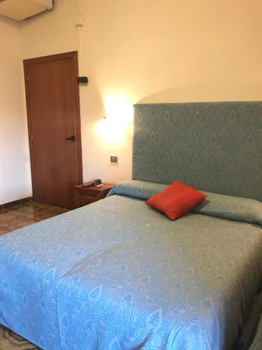 a bedroom with a blue bed with a red pillow at Hotel Scala Greca in Syracuse