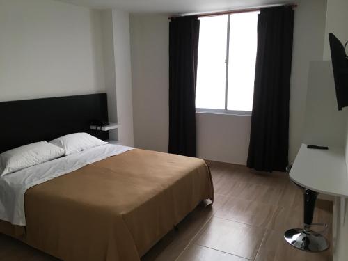 a bedroom with a bed and a desk and a window at Hotel Villa Blanca in Popayan