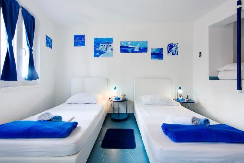two beds in a room with blue pillows at Old City Rooms in Zadar