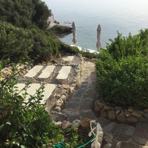 a stone path next to the ocean with trees at Rosys Little Village in Skala