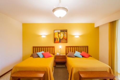 two beds in a room with yellow walls at Hotel Posada Loma in Fortín de las Flores