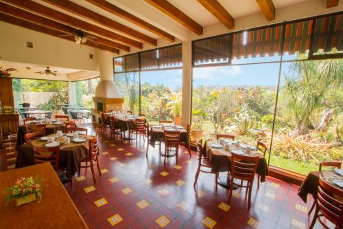 a restaurant with tables and chairs and large windows at Hotel Posada Loma in Fortín de las Flores