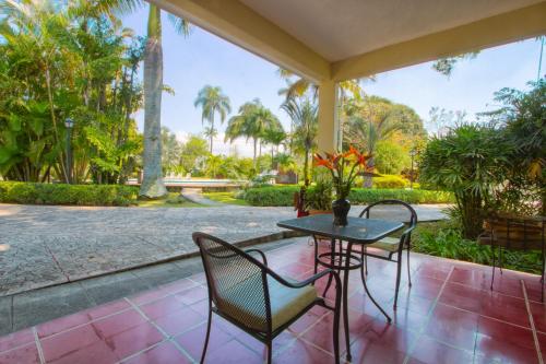 a table and chairs on a porch with palm trees at Hotel Posada Loma in Fortín de las Flores