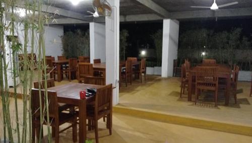 een leeg restaurant met houten tafels en stoelen bij Samwill Holiday Resort in Kataragama