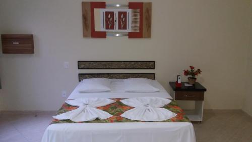 a bedroom with a bed with white sheets and pillows at Pousada Palmares in Cabo Frio