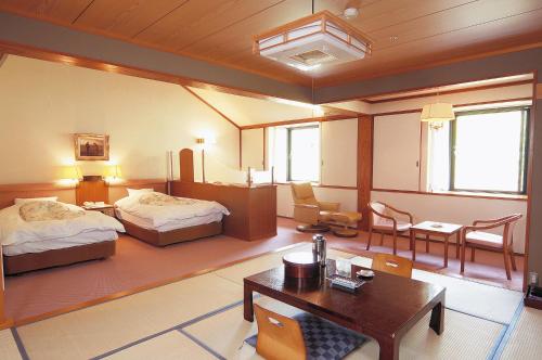 a hotel room with two beds and a table and chairs at Watarase Onsen Hotel Sasayuri in Hongu