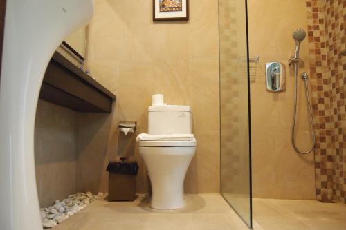 a bathroom with a toilet and a glass shower at Yulia Village Inn Ubud in Ubud
