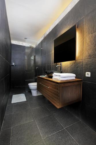 a bathroom with a toilet and a television on the wall at Villa Sunset Jogjakarta in Yogyakarta