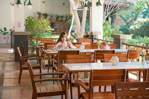 a woman sitting at a table in a restaurant at Muaklek Paradise Resort in Ban Muak Lek