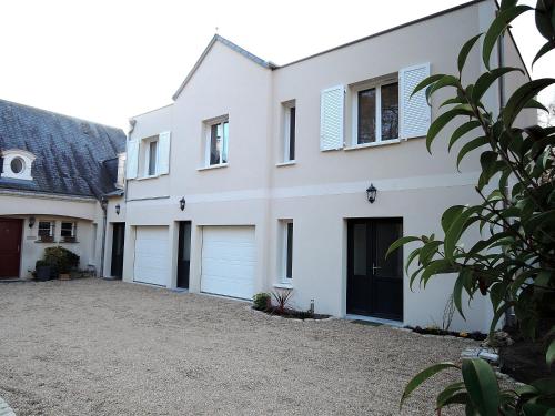 a white house with two garage doors at Logis du Lièvre d'or in Montbazon