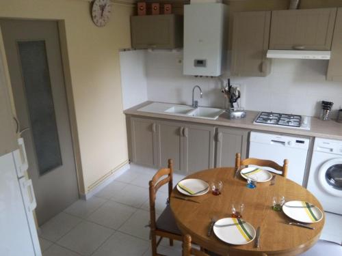 - une cuisine avec une table en bois, des chaises et un évier dans l'établissement Maison JMB, à Royan