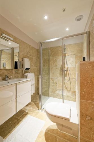 a bathroom with a shower and a toilet and a sink at Pied à Terre - Appart'hôtels au coeur d'Autun in Autun