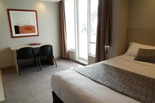 a hotel room with a bed and a desk at Parkville Place Serviced Apartments in Melbourne