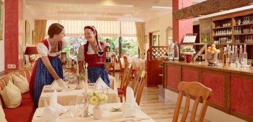 two women are standing at a table in a restaurant at Ringhotel Bömers Mosel Landhotel in Alf