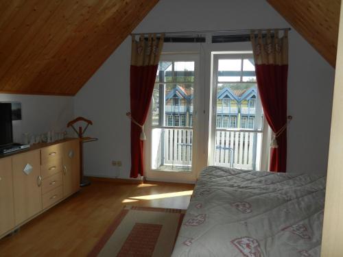 ein Schlafzimmer mit einem Bett und zwei großen Fenstern in der Unterkunft Ferienhaus Schoen in Rheinsberg
