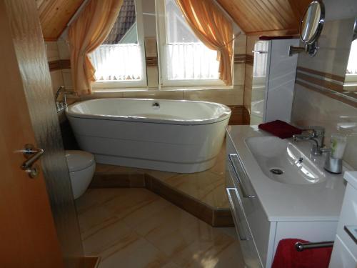 a bathroom with a tub and a toilet and a sink at Ferienhaus Schoen in Rheinsberg