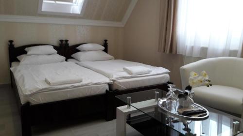 a bedroom with two beds and a table and a chair at Kemence Csárda és Szálloda in Nyíregyháza