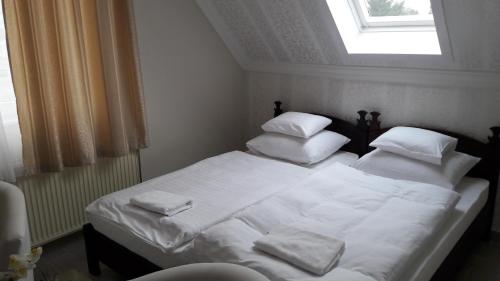 a bedroom with a bed with white sheets and pillows at Kemence Csárda és Szálloda in Nyíregyháza