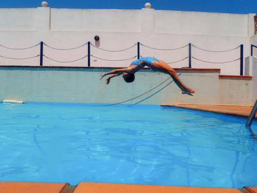 a man jumping into a pool in a swimming pool at Apartamento con terraza in Tarifa