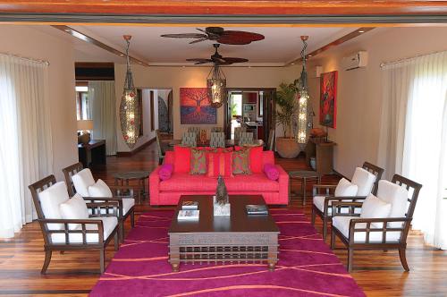 a living room with a pink couch and chairs at Sankhara Private Beach Luxury Villas in Poste Lafayette