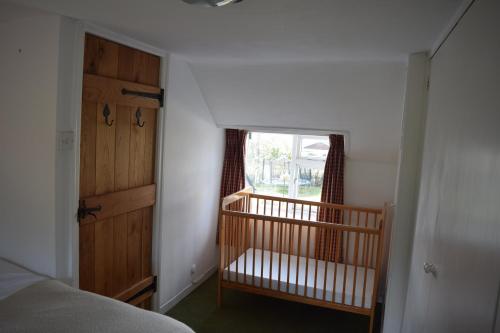 una camera da letto con una culla accanto a una finestra di Ceiros Cottage a Llangammarch Wells