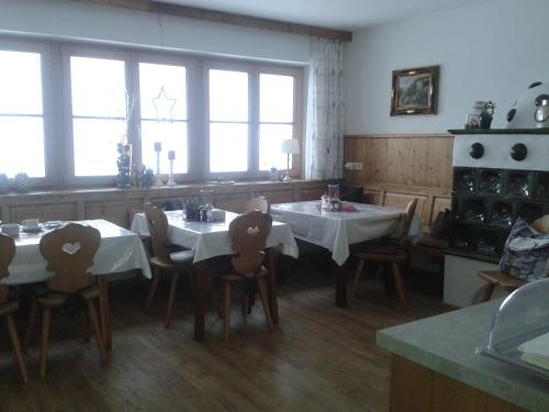 a dining room with two tables and chairs and windows at Biobauernhof Windbachgut in Eben im Pongau