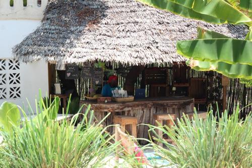 a woman sitting at a bar in a straw hut at Zanzistar Lodge in Jambiani