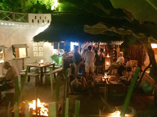 a group of people sitting in a restaurant at night at Zanzistar Lodge in Jambiani