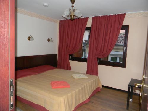 a bedroom with a bed with red curtains and a window at House Diona in Sozopol