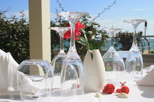 a table with wine glasses and a red flower in a vase at Aregai Marina Hotel & Residence in Santo Stefano al Mare