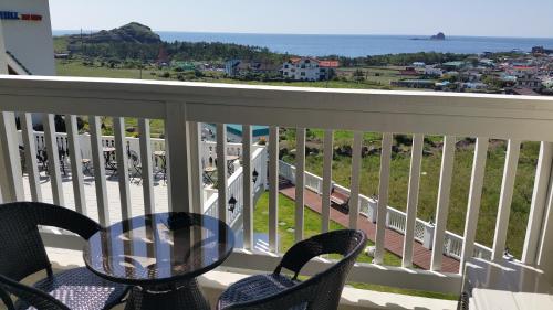 a balcony with a table and chairs and the ocean at Jeju the Ocean Hill Pension in Seogwipo