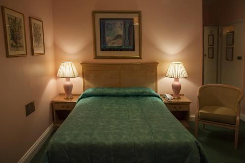 a bedroom with a green bed and two lamps at Her Majesty Hotel in London