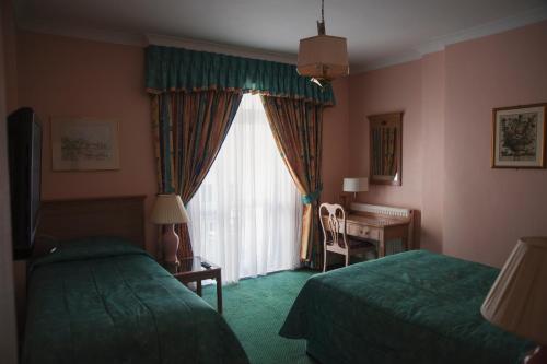 a hotel room with two beds and a window at Her Majesty Hotel in London