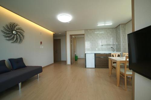 a living room with a couch and a table and a kitchen at Jeju the Ocean Hill Pension in Seogwipo