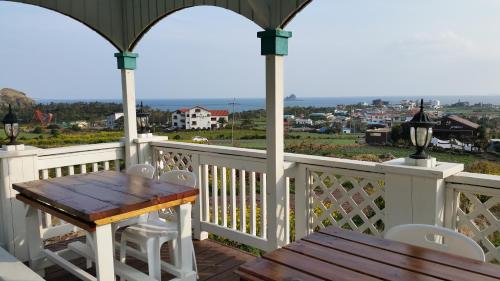 a wooden table and chairs on a porch with a view at Jeju the Ocean Hill Pension in Seogwipo