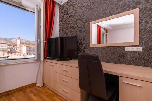 a room with a desk with a television and a mirror at Heritage Hotel Vila Sikaa in Trogir