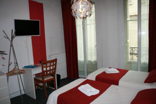 a hotel room with two beds and a desk and a chair at Hôtel Le Chambellan in Dijon