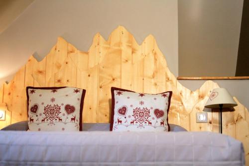 a bed with two pillows and a wooden headboard at Auberge Le Cabaliros in Argelès-Gazost