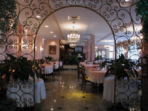 uma sala de jantar com mesas e cadeiras e um portão em Hotel Eden em Grado