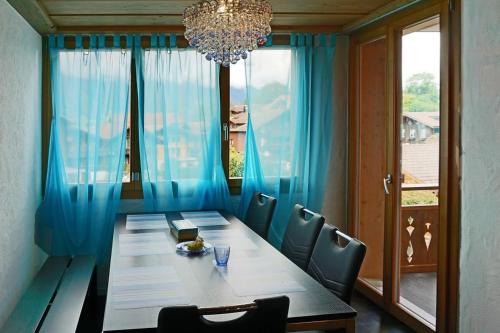 a dining room table with blue curtains and a chandelier at Switzerland Iseltwald Apartment in Iseltwald
